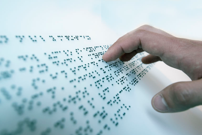 Informatiebord met braille en een hand die voelt