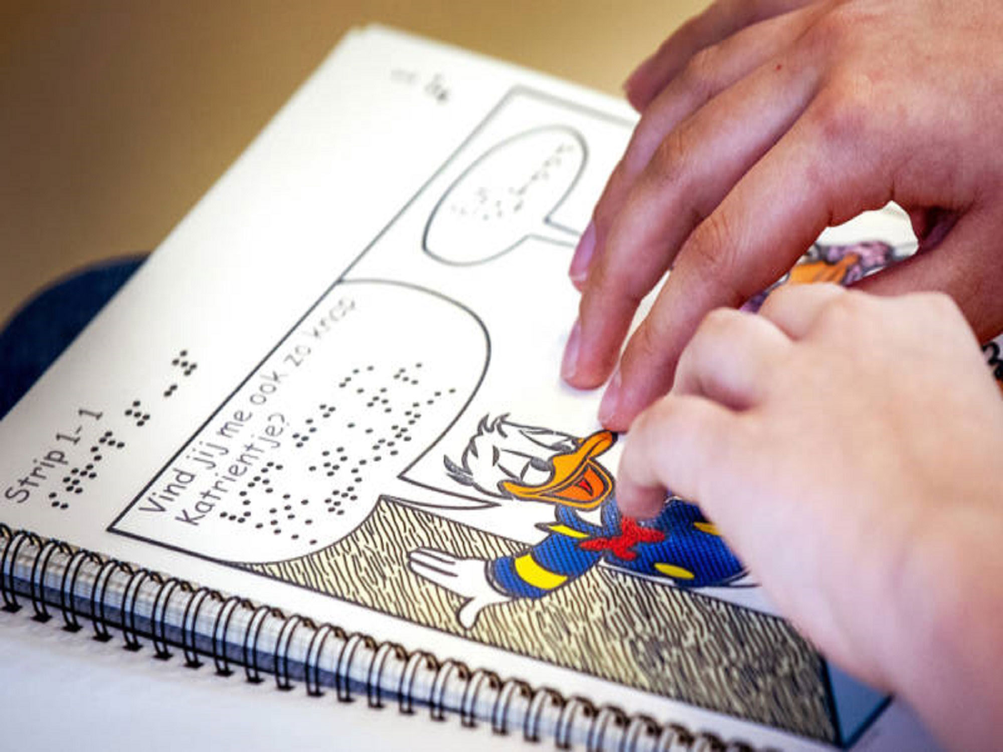 twee handen lezen een donald duck in braille