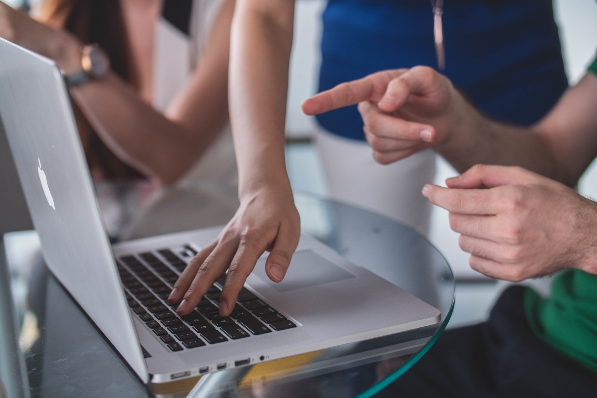 Twee paar handen bij een laptop. Een hand wijst op beeldscherm