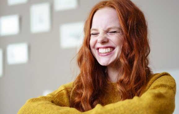 Jonge vrouw lacht met ogen dicht geknepen