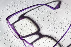 drukwerk in braille met daarbovenop een bril