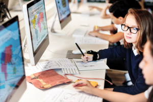 leerlingen naast elkaar aan een bureau kijken op beeldschermen met vergrotingen wereldkaart