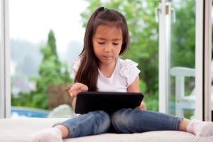 meisje zit op een kussen met tablet op schoot