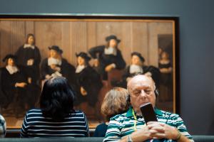man met koptelefoon in Rembrandthuis voor een groepsportret door Ferdinand Bol