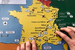 Handen voelen een overzichtskaart in reliëf van de Tour de France 2019