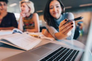 drie personen aan een bureau in overleg; een van de mensen wijst met een pen op een beeldscherm