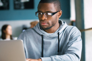 afbeelding van een persoon met bril die op een laptop kijkt