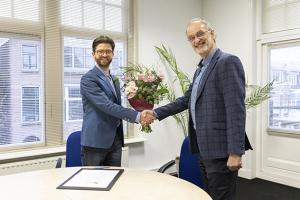 AMN-directeur Wouter van der Neut ontvangt bloemen en felicitaties van Paul Gillijns (Mediafederatie)