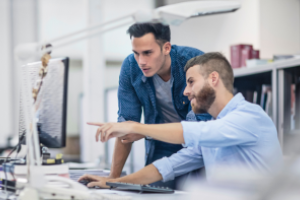 2 personen zijn in overleg en wijzen naar het computerscherm