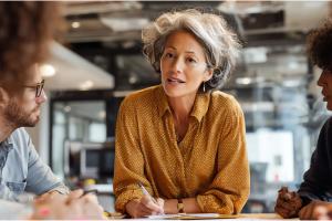 een vrouw zit in een bespreking met een team