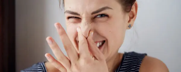 een vrouw knijpt haar neus dicht alsof ze iets smerigs ruikt