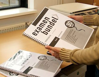 twee handen houden een examenbundel in A3-formaat vast