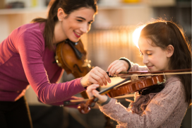 Muziekdocent helpt leerling bij het bespelen van een viool