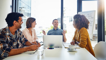 groep mensen aan vergadertafel, waarop iemand achter een laptop werkt
