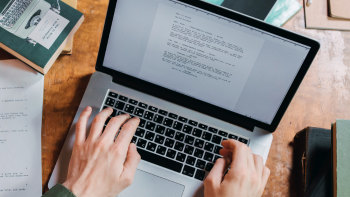 afbeelding van handen typend op een toetsenbord en beeldscherm met daarop tekst