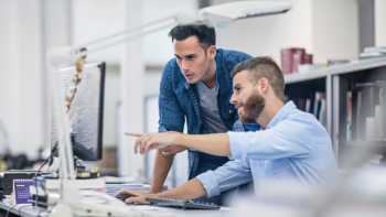 2 personen zijn in overleg en wijzen naar het computerscherm