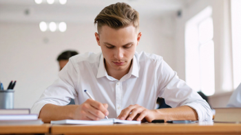 student met pen en boek aan werktafel in een klaslokaal